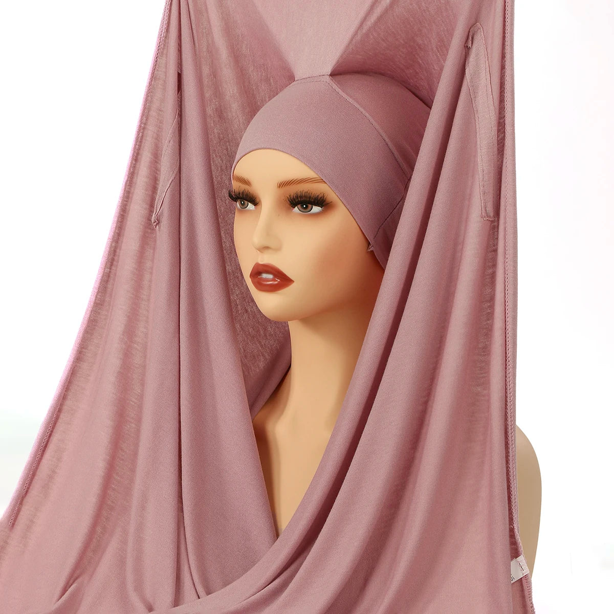 Ein Modell trägt ein staubrosa Modal-Jersey-Hijab, elegant um ihren Gesicht drapiert.