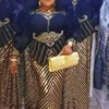 A woman models a gold and black sequin African party dress with dark fur accents.