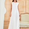 A woman wearing a white flowing modest abaya dress in a light beige room.