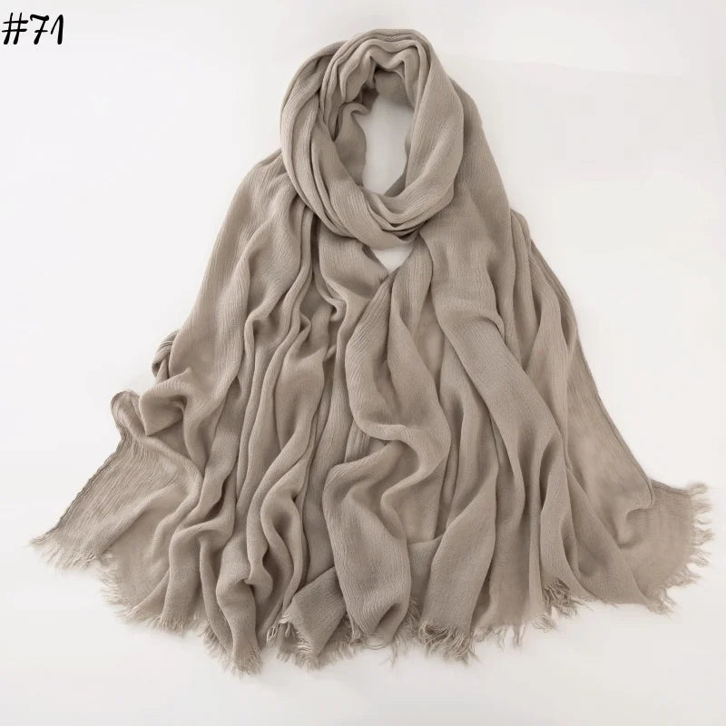 Un foulard hijab en coton viscose beige doux, drapé et plié sur un fond blanc.