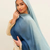 Una mujer vistiendo un pañuelo hijab con degradado azul y una blusa color crema.