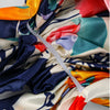 Tela de pañuelo de satén colorido, drapeado y doblado, mostrando varios tonos de azul, naranja, rosa y crema