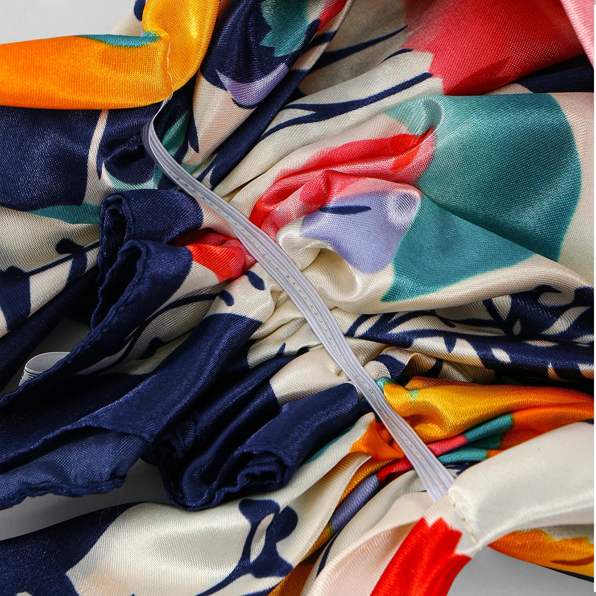 Nahaufnahme eines satinbedruckten Hijab-Turban mit Blumenmustern in Blau-, Rot-, Orange- und Cremetönen.