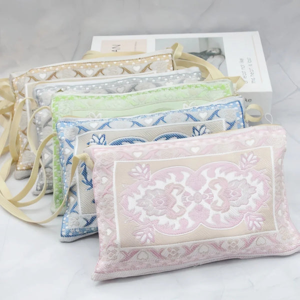 A collection of Muslim prayer mats in various pastel colors and patterns, including a portable bag.