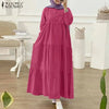 Eine Frau modelliert ein langes, fließendes magentafarbenes muslimisches Abaya-Kaftan-Kleid in einem hellen Innenraum.