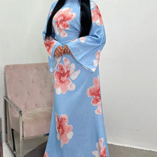 Une femme portant une caftan abaya bleu clair à motif floral avec des accents roses.