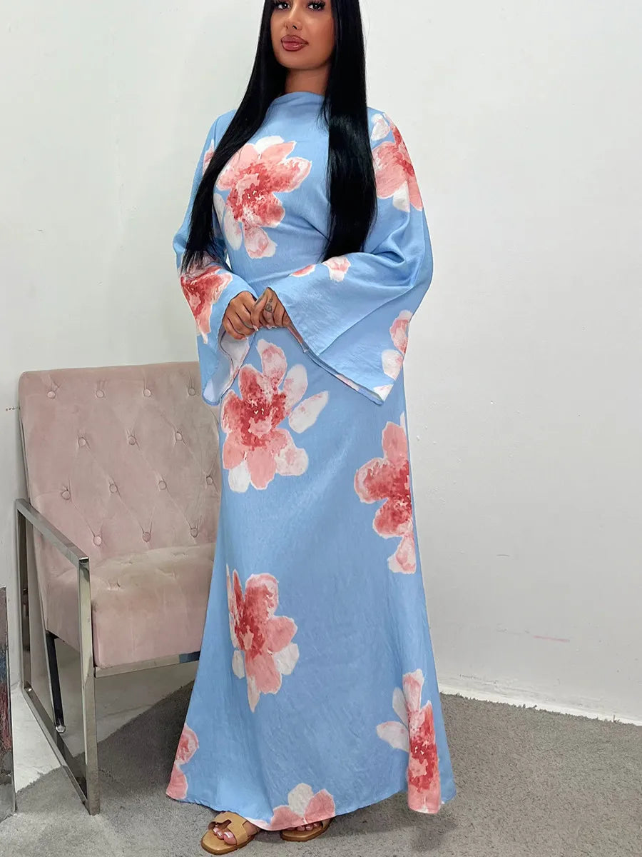 A woman wearing a light blue abaya kaftan dress with a floral print and pink accents.