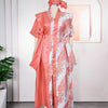 A woman wearing an elegant flowing pink kaftan with white tatting detail, displayed on a mannequin.
