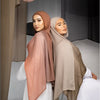 Une femme portant un foulard hijab fluide à dégradé de rose poudré et de beige.