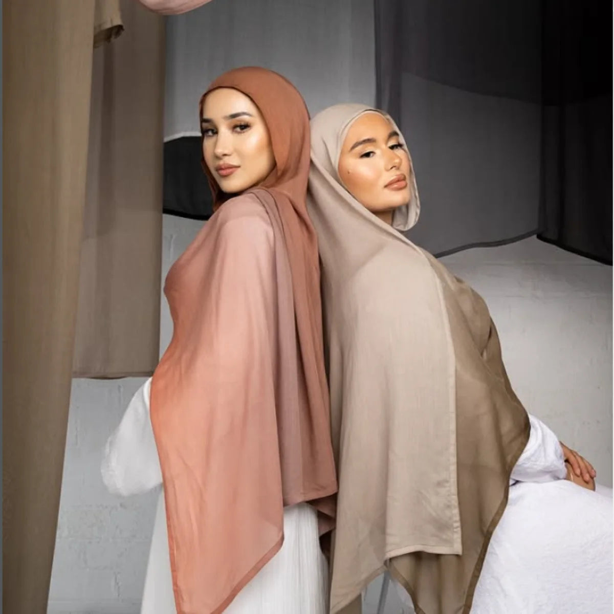 Une femme portant un foulard hijab fluide à dégradé de rose poudré et de beige.