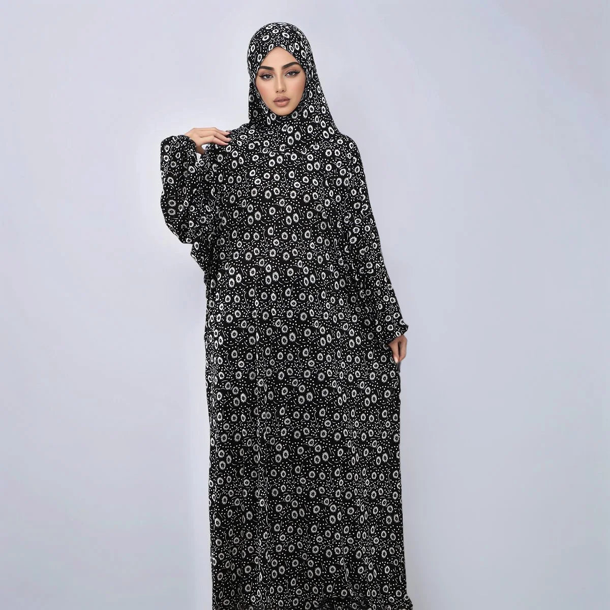 A woman wearing an elegant black and white patterned Muslim hijab dress.