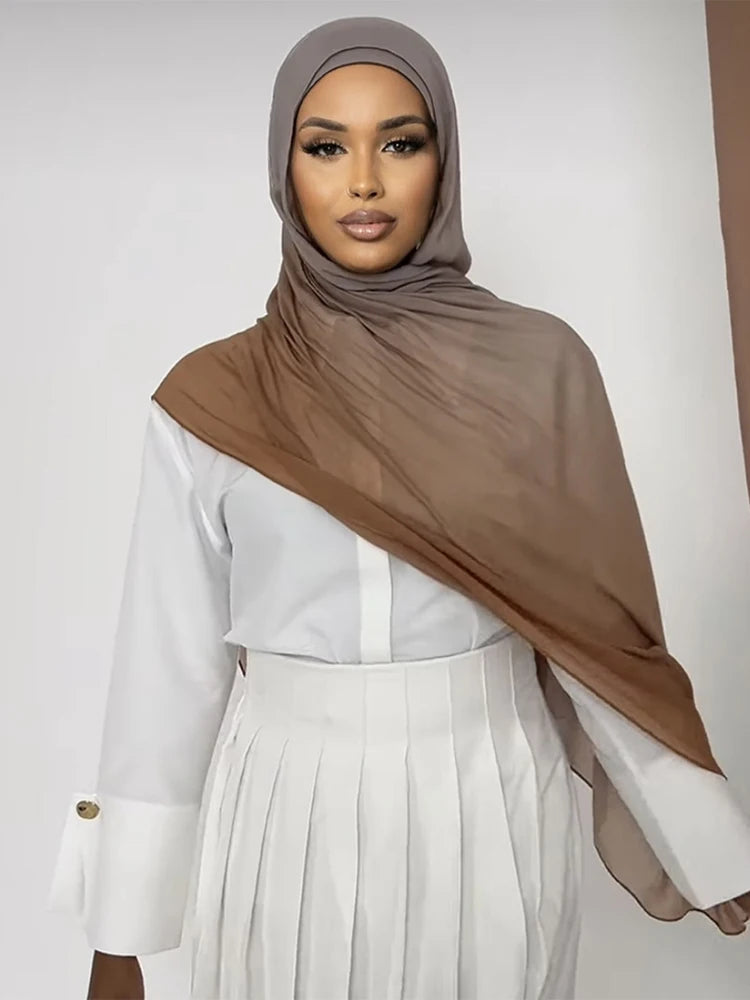 Eine Frau trägt einen braunen Ramanda Bamboo Modal Rayon-Schal-Hijab über einem weißen Oberteil und einem plissierten Rock.