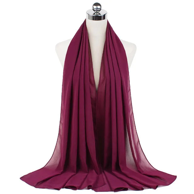 A deep magenta chiffon hijab scarf draped around a mannequin's neck.