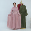 Une femme modélise une abaya en mousseline rose fluide avec une ceinture ornée et une tenue assortie verte.