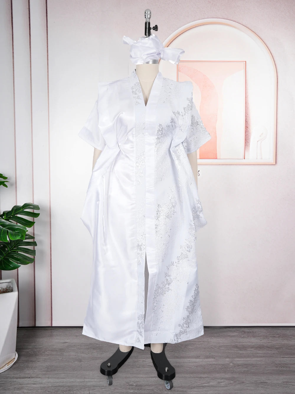 A white elegant flowing kaftan for women with silver tatting detail displayed on a mannequin.