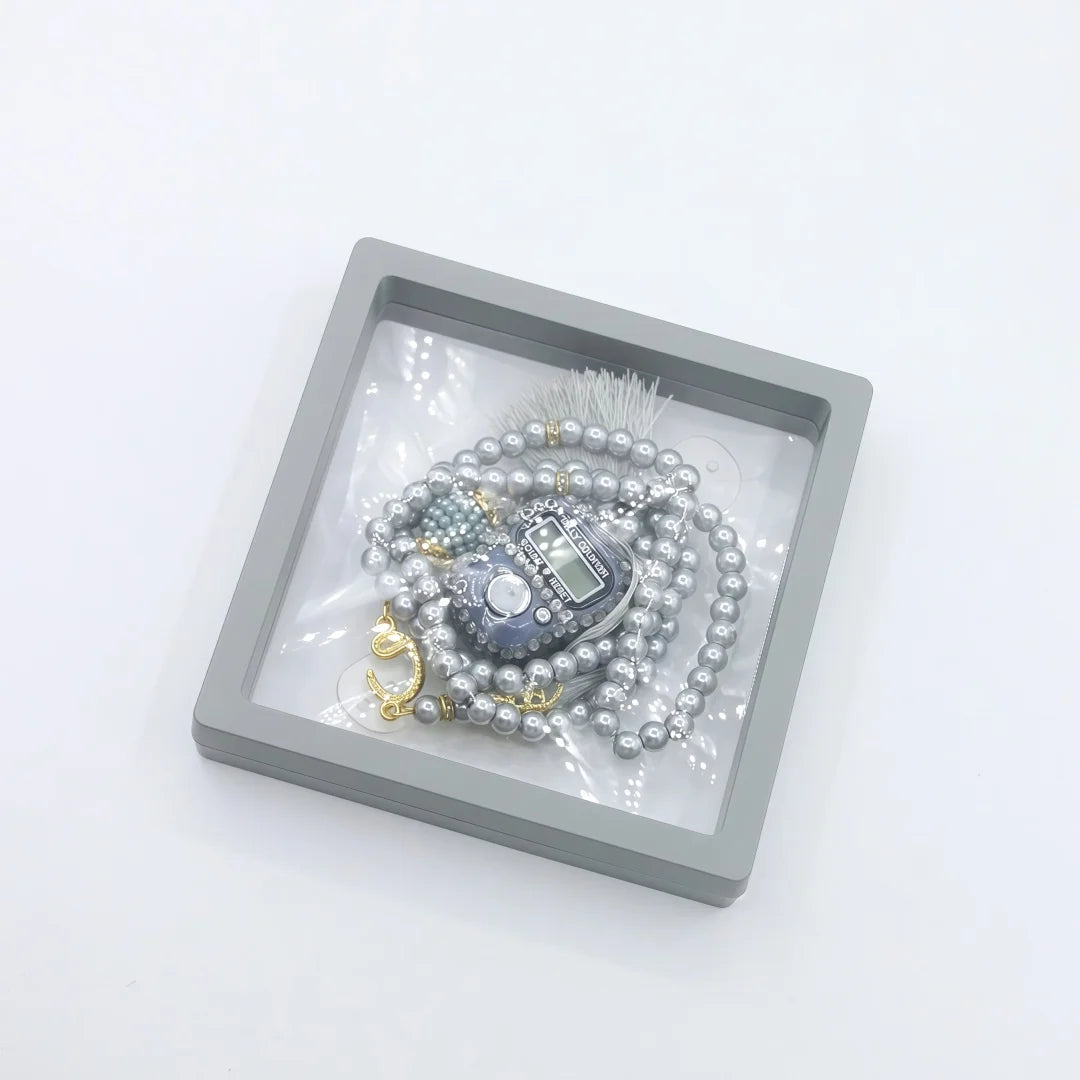 A silver-toned box holds an Islamic tasbih prayer beads and a digital counter bracelet.