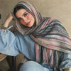Una mujer vistiendo un pañuelo de hijab floral de acuarela bohemio a rayas y una camisa de mezclilla.