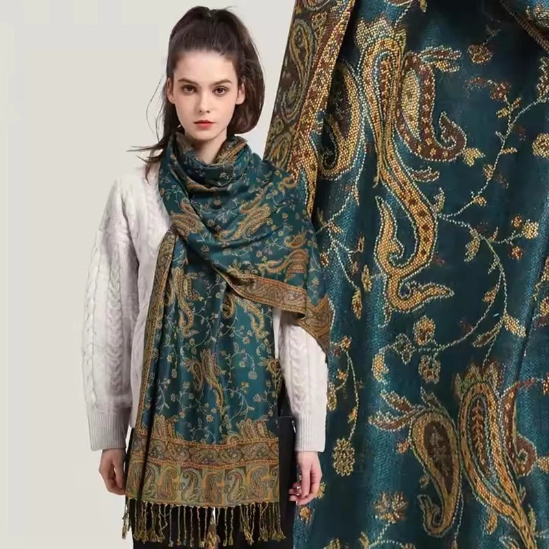 Model trägt einen eleganten türkis-goldenen Paisley-Viskose-Hijabschal über einem weißen Pullover.