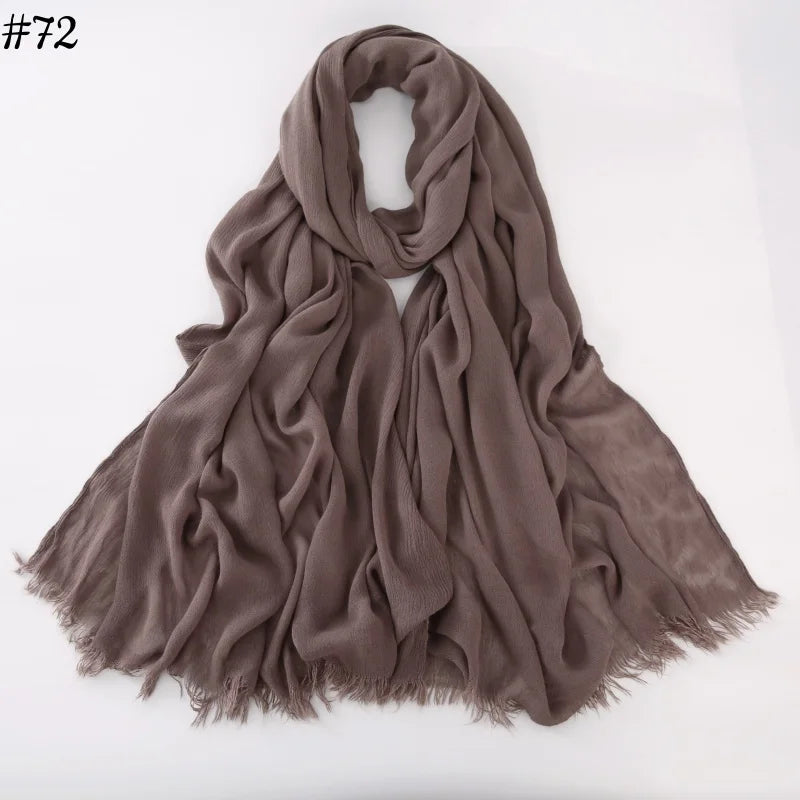 Un foulard hijab de viscose brun doux drapé et plié sur un fond blanc.