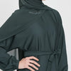 Eine Frau trägt eine dunkeltürkise marokkanische Kaftan-Abaya mit langen Ärmeln und einem drapierten Kopftuch.