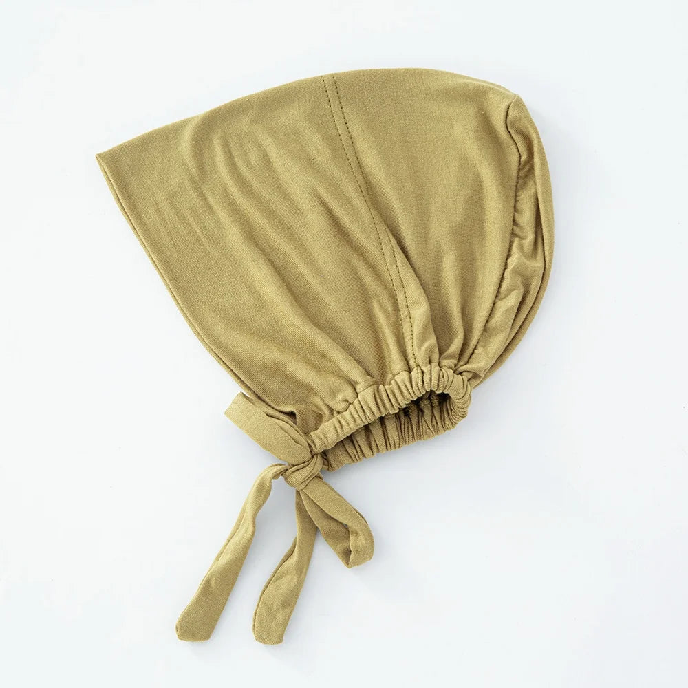 Ein fester olivgrüner Tuch, das als inneres Hijab-Bonnet gefaltet und unten zusammengebunden ist.