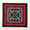Carré de tissu noir avec un motif répétitif de crânes et d'os blancs sur fond rouge.