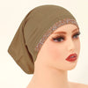 Cabeza de maniquí con hijab elástico de algodón modal beige y ribete dorado brillante.