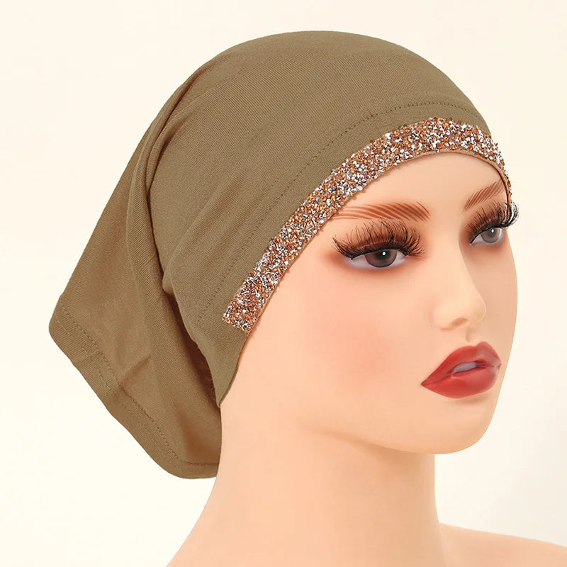 Cabeza de maniquí con hijab elástico de algodón modal beige y ribete dorado brillante.