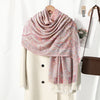 Chal vintage de bordado paisley rosa y beige sobre un abrigo crema.