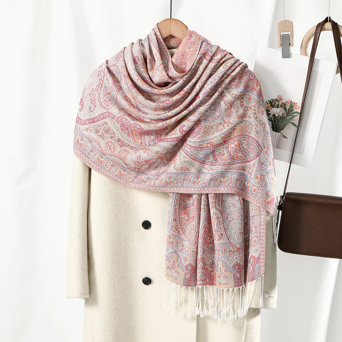 Chal vintage de bordado paisley rosa y beige sobre un abrigo crema.