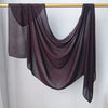 Écharpe hijab de couleur prune foncée drapée sur un cintre en bois.
