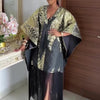 Eine Frau modelliert ein traditionelles afrikanisches Dashiki Maxi-Kleid mit Gold- und Schwarzmustern.
