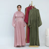Une femme modélise une abaya rose fluide avec une ceinture ornée, à côté d'une abaya verte.