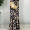 Una mujer vistiendo una elegante kaftan abaya floral con mangas largas y un bolso de hombro tejido beige.
