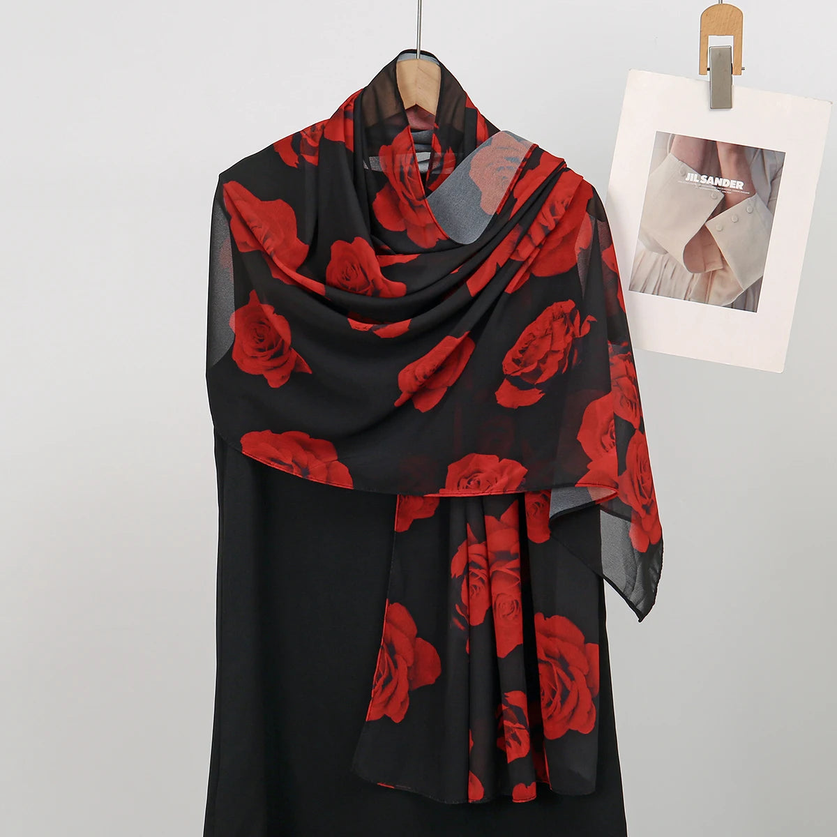 Una bufanda de gasa negra con estampado floral rojo drapeada sobre un maniquí.