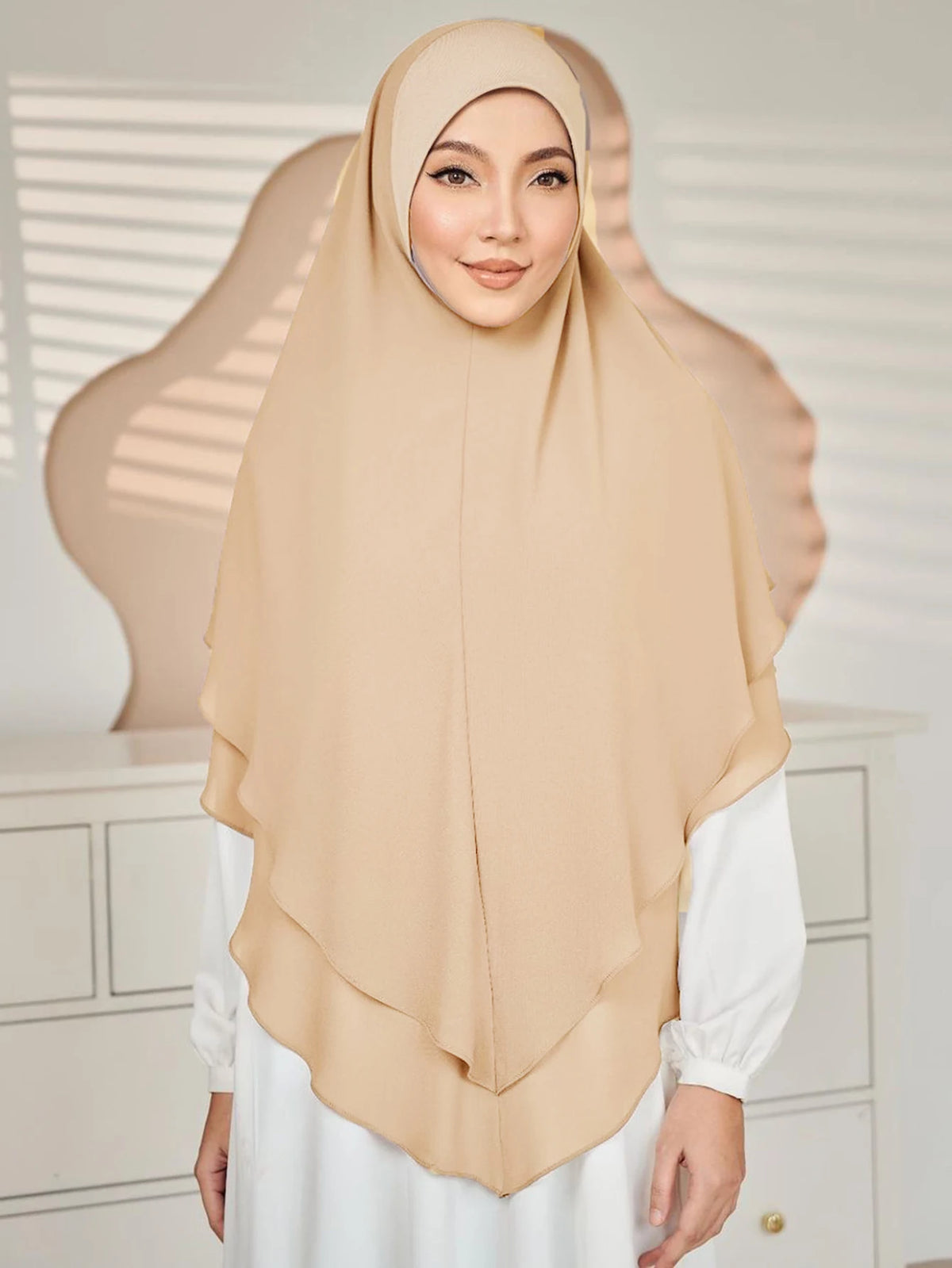 Eine Frau trägt einen beige-beigen doppelten Chiffon-Instant-Hijab-Schal mit einem weißen Oberteil.