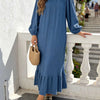 Une femme portant une longue robe maxi bohème bleue à volants, debout à l'extérieur.