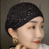 Nahaufnahme einer Frau mit einem eleganten schwarzen elastischen Turbanhut, verziert mit Gold-Strass.