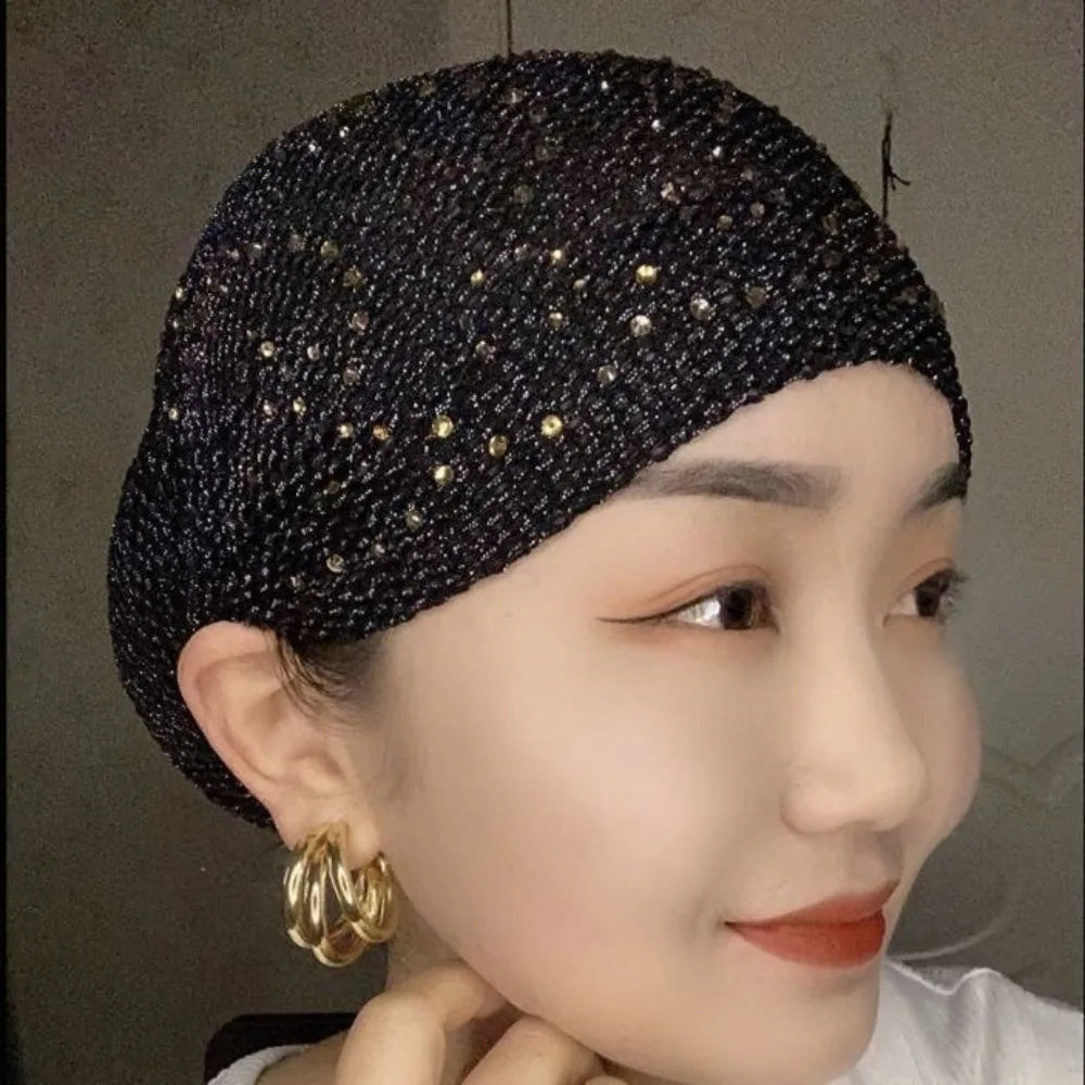 Nahaufnahme einer Frau mit einem eleganten schwarzen elastischen Turbanhut, verziert mit Gold-Strass.