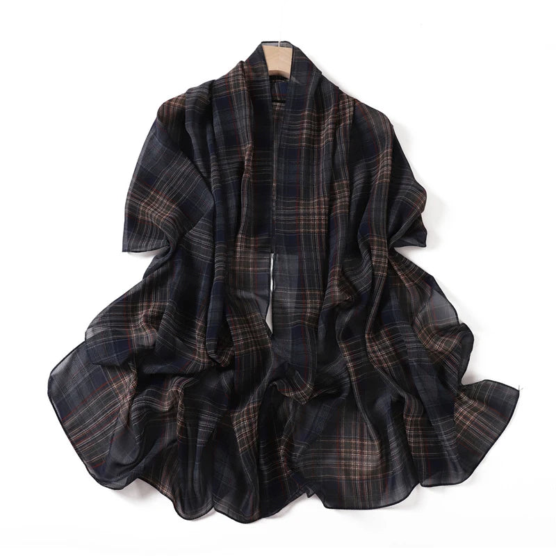 Pañuelo de chifón largo con estampado de tartán oscuro colgado en una percha.