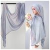 Eine Frau trägt einen hellblauen Aquarell-Ombré-gedruckten Rayon-Modal-Hijabschal über Kopf und Schultern.