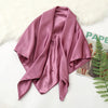 A draped, solid mauve silk satin hijab scarf laid on a white surface next to a green fern.