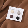 Weißer Magnethalter mit vier runden, matten Hijab-Magneten in Beige, Grau, Braun und Schwarz auf brachem Stoff