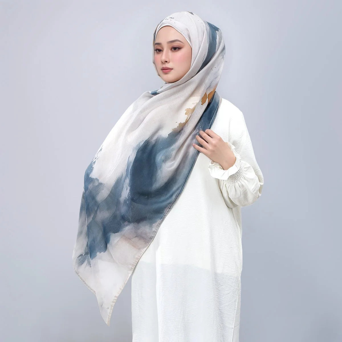 Eine Frau trägt einen Aquarell-Linen-Seidenschal mit islamischem Muster über Kopf und Schultern, kombiniert mit einem weißen 