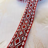 Primer plano de una cinta jacquard geométrica roja y blanca con formas de diamante.