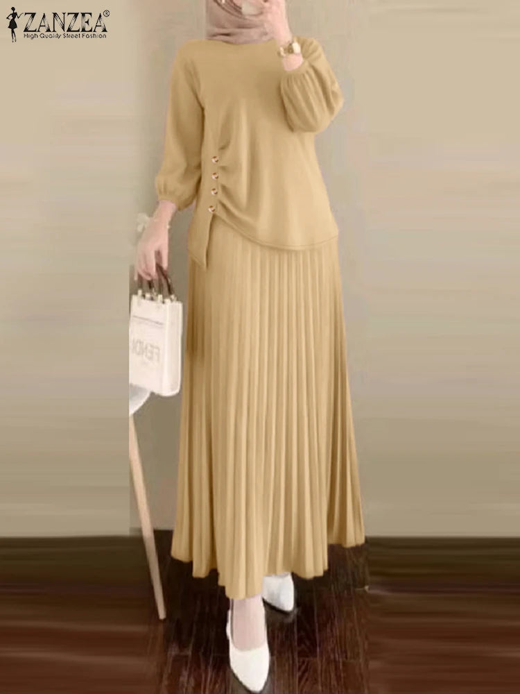 Une femme portant une longue robe beige et un foulard assorti, debout à l'intérieur.
