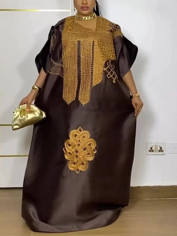 A woman wearing a dark brown traditional Ankara dashiki gown with gold embroidery and sleeves.