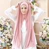 Femme portant un foulard instant en jersey rose et élastique avec des vêtements blancs, entourée de compositions florales.