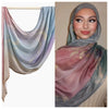 Nahaufnahme einer Frau, die einen Aquarell-Ombré-bedruckten Seiden-Modals-Hijabschal in Rosa-, Lila- und Grautönen trägt.