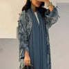 Eine Frau trägt eine fließende blau-tiegedruckte Abaya-Kaftan mit langen Ärmeln und einem passenden Schal.